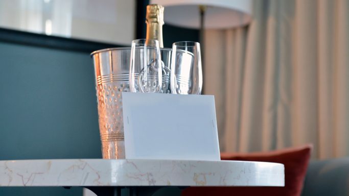 Ein Tisch mit Sektflasche, Gläsern und einer leeren weißen Karte.